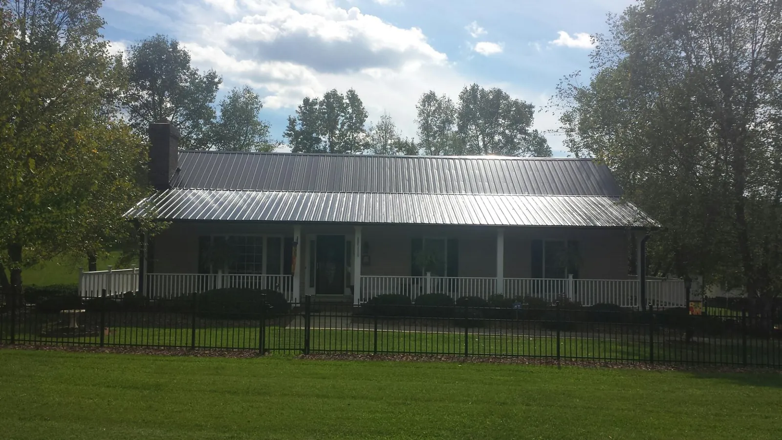 Gray metal roof on a brick ranch with a full width front porch — Gutter Guard Installation work by our crew in New London